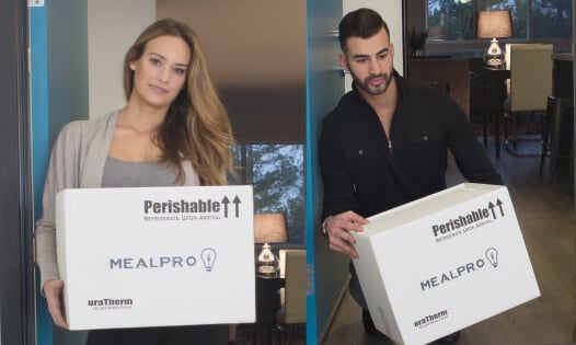 A woman and man holding a MealPro box at their house