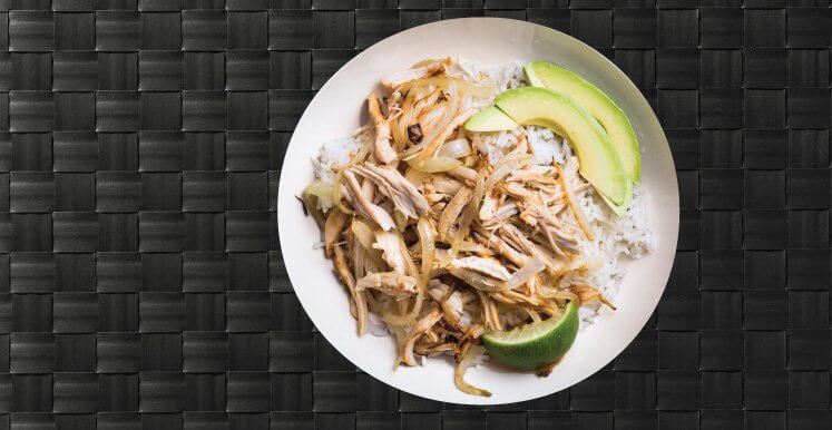 Pictured is a chicken and rice meal on a plate with an avocado side.