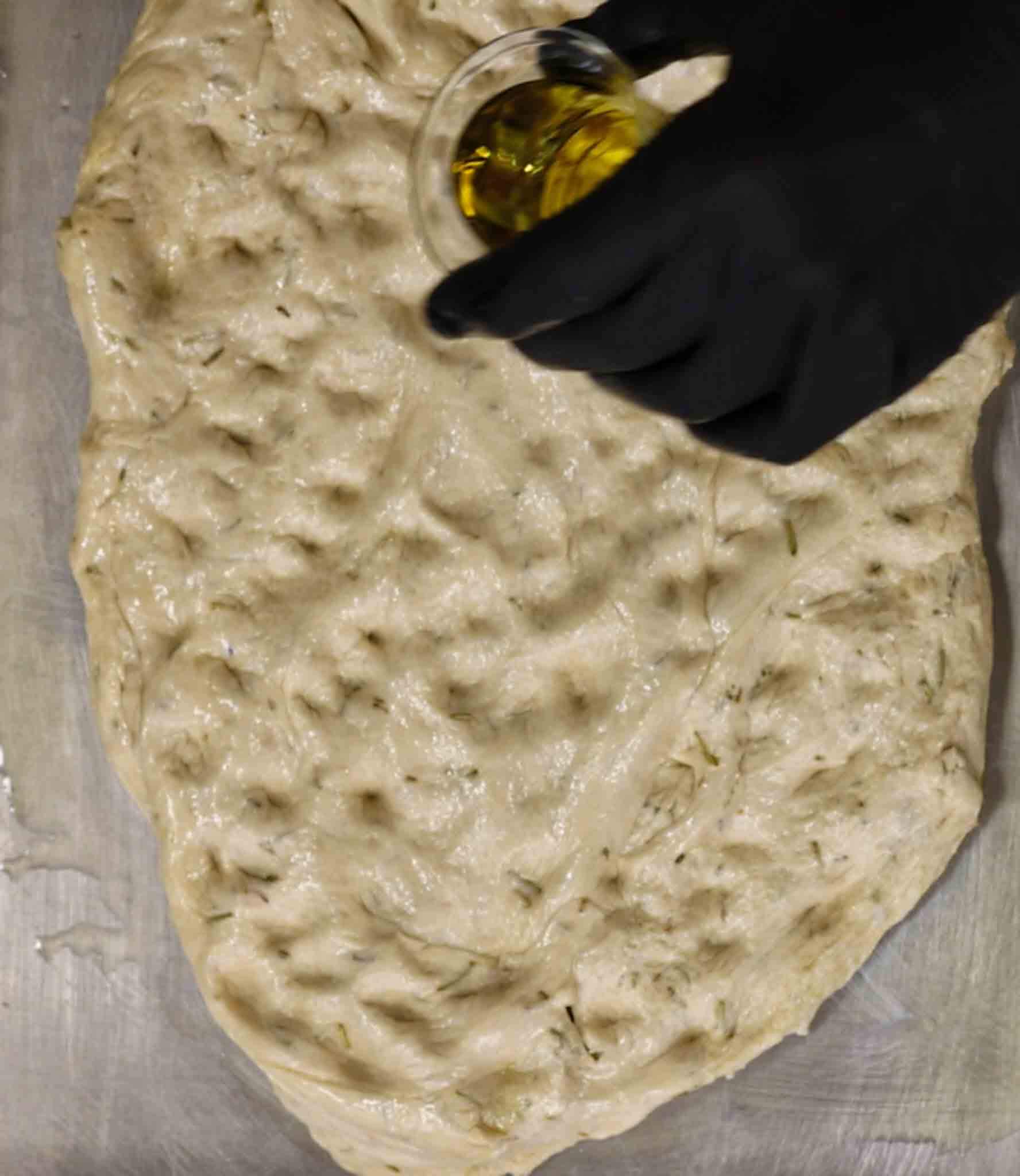 filling the focaccia dough with olive oil